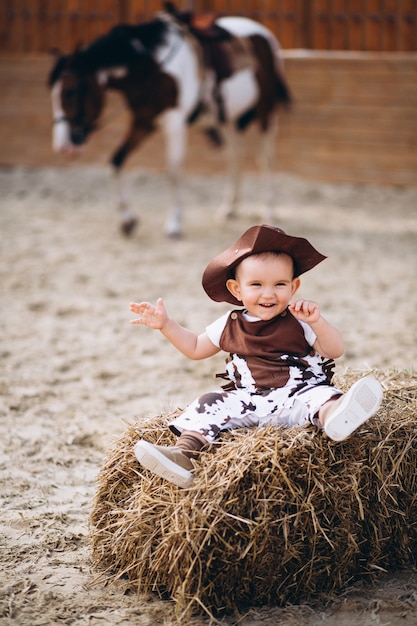 Kleiner cowboy, der auf heu sitzt