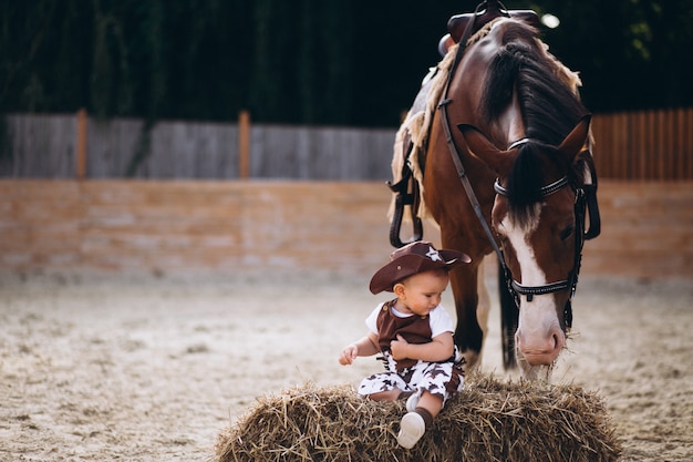 Kostenloses Foto kleiner cowboy, der auf heu sitzt