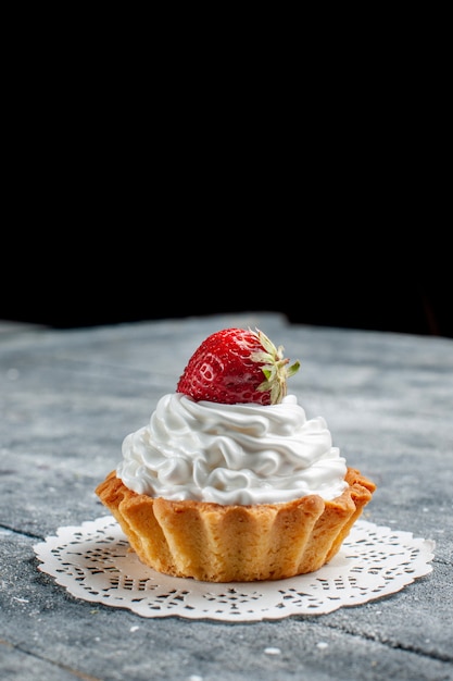 kleiner cremiger Kuchen, köstlich gebacken mit Erdbeere auf grauem hellem Schreibtisch, Kuchen süßer Sahnezucker