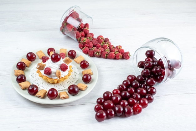 kleiner cremiger Kuchen mit Sauerkirschen und Himbeeren auf weißem, frischem Obstbeerenkuchen süß