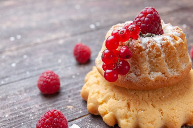 kleiner einfacher Kuchen mit Zuckerpulver Himbeere und Preiselbeeren auf rustikalem Schreibtisch