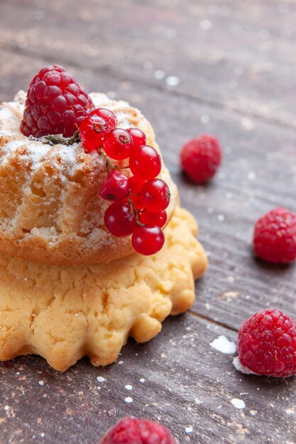 kleiner einfacher Kuchen mit Zuckerpulver Himbeere und Preiselbeeren auf rustikalem Schreibtisch