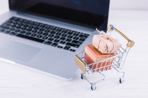 Kleiner Einkaufswagen mit Geschenkboxen und Laptop