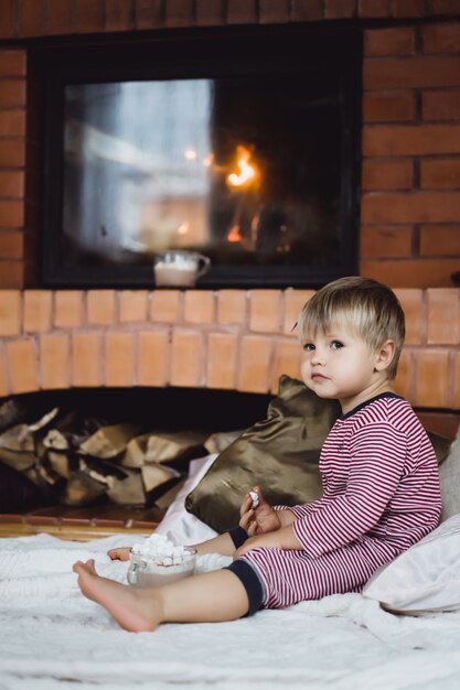 Kleiner Junge am Feuer und heiße Schokolade mit Marshmallows