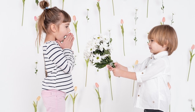 Kostenloses Foto kleiner junge, der dem mädchen blumen gibt