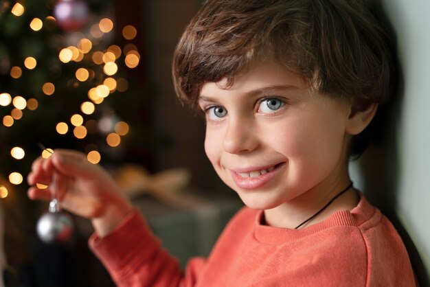 Kostenloses Foto kleiner junge, der den weihnachtsbaum schmückt