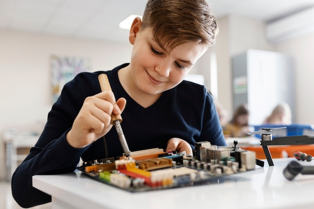 Kleiner Junge, der ein elektronisches Bauteil repariert