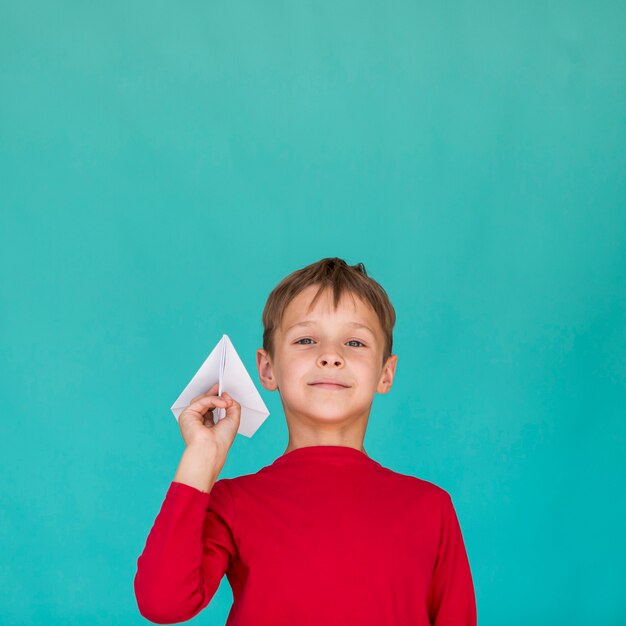 Kleiner Junge, der ein Papierflugzeug hält