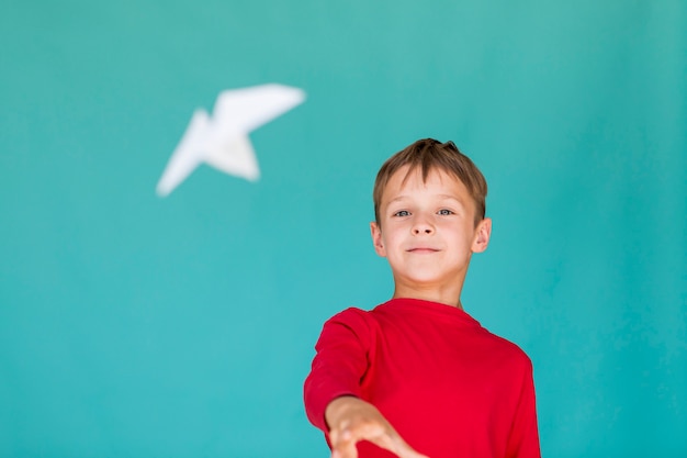 Kleiner Junge, der ein Papierflugzeug wirft