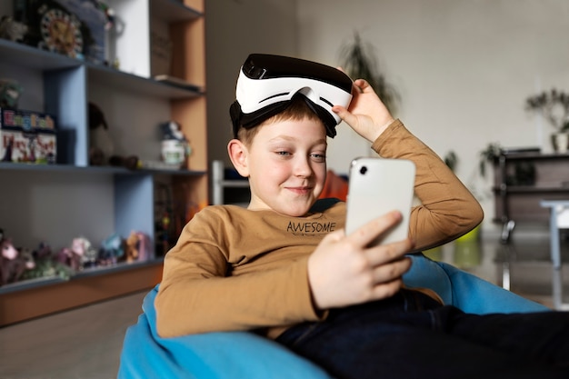 Kleiner Junge, der eine VR-Brille ausprobiert und sein Smartphone benutzt