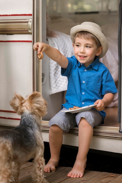 Kleiner Junge, der einen Teller neben einem niedlichen Hund hält