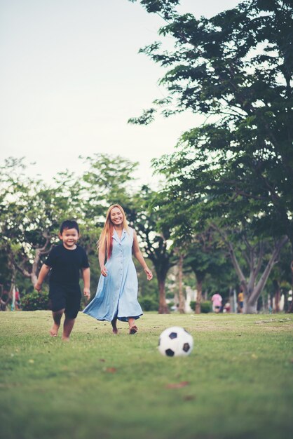 Kleiner Junge, der Fußballfußball mit Mutter im Park spielt