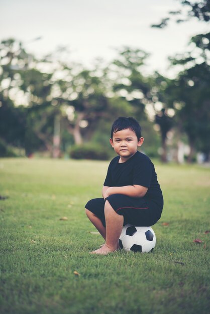 Kleiner Junge, der Fußballfußball spielt