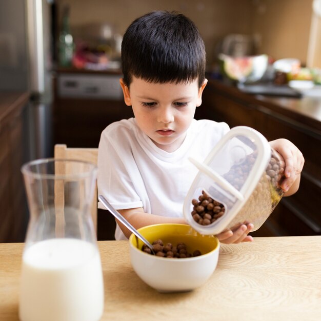 Kleiner Junge, der Getreide mit Milch isst