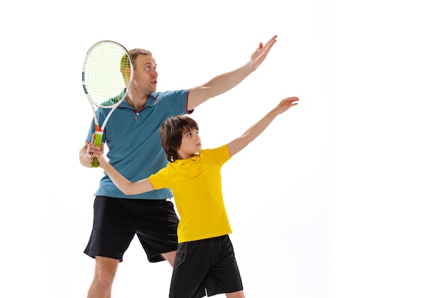 Kleiner Junge, der lernt, wie man Tennis spielt, mit professionellem Sportlehrer isoliert auf weißem Studiohintergrund