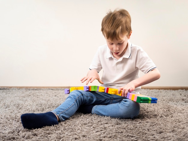 Kleiner Junge, der mit buntem Blockspiel spielt