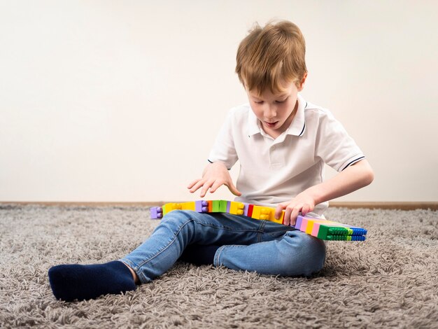 Kleiner Junge, der mit buntem Blockspiel spielt