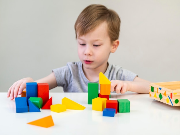 Kleiner Junge, der mit bunten Würfeln spielt