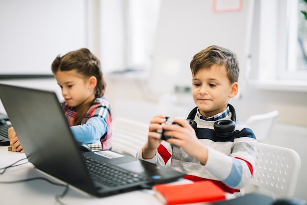 Kleiner Junge, der mit dem Mädchen im Klassenzimmer spielt mit Würfelpuzzlespiel sitzt