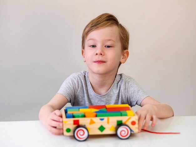 Kleiner Junge, der mit interessantem Holzauto spielt