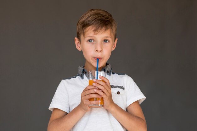 Kleiner Junge, der Orangensaft trinkt