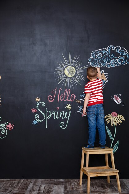 Kleiner Junge, der Ostern Kritzeleien steht und zeichnet