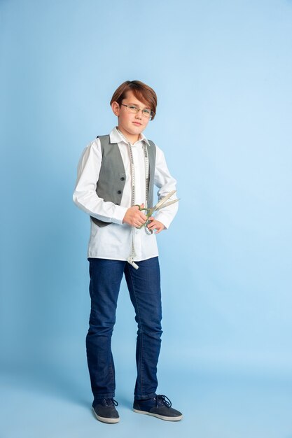 Kleiner Junge, der vom zukünftigen Beruf der Näherin träumt. Kindheits-, Bildungs- und Traumkonzept. Will erfolgreicher Mitarbeiter in der Mode- und Stilbranche werden, macht Atelier Kleidung. Copyspace.