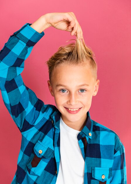 Kleiner Junge des smiley, der mit seinen Haaren spielt