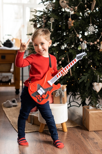 Kostenloses Foto kleiner junge hält eine gitarre