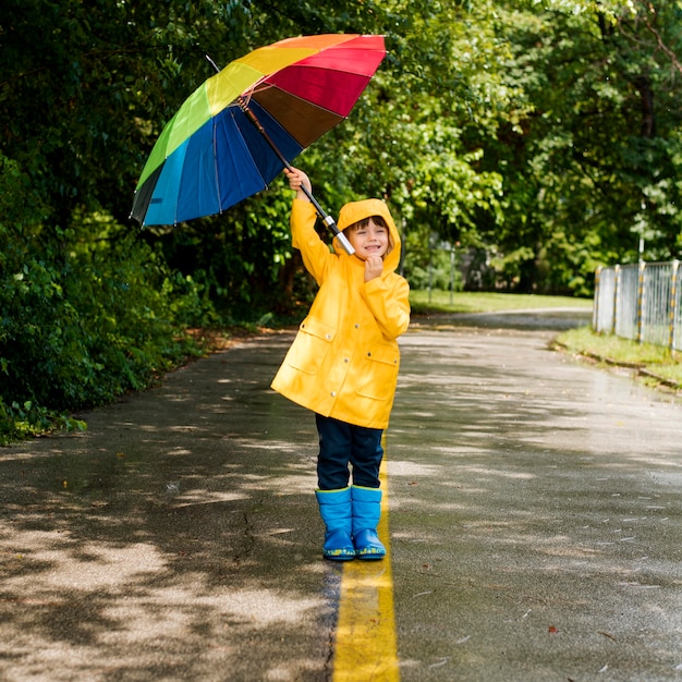 Kleiner Junge hält einen Regenschirm über seinem Kopf