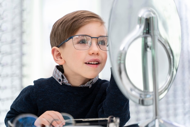 Kleiner Junge im Laden, der Brille anprobiert