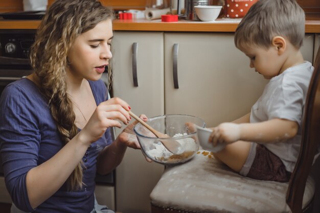 kleiner Junge in der Küche hilft Mama beim Kochen. Das Kind ist am Kochen beteiligt.