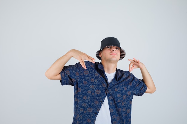 Kleiner Junge in weißem T-Shirt, Blumenhemd, Mütze mit OK-Zeichen und Handgesten und selbstbewusstem Blick