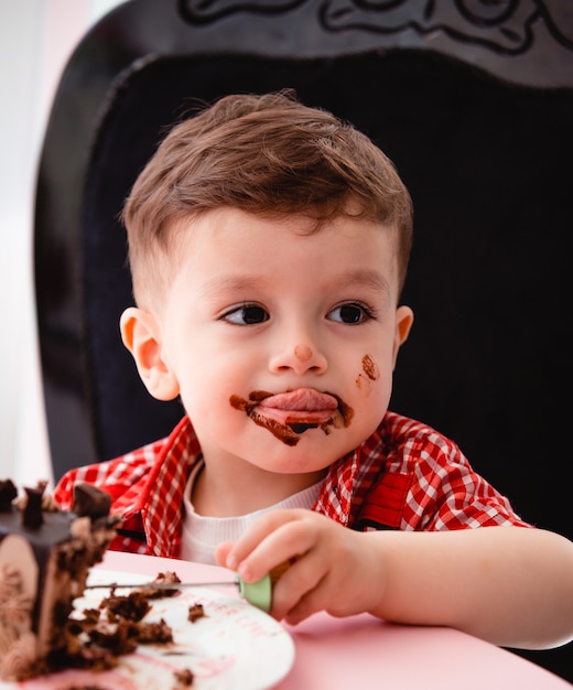 Kleiner Junge isst Kuchen und wird schmutzig
