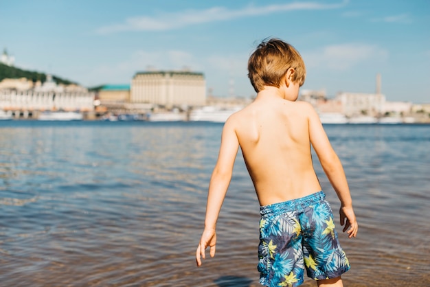 Kostenloses Foto kleiner junge kommt in den fluss