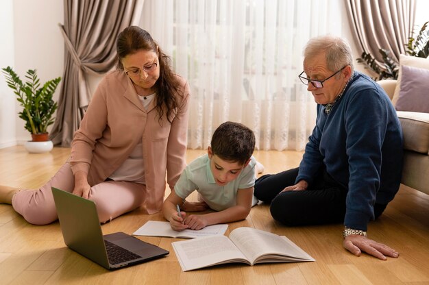Kleiner Junge macht Hausaufgaben mit seinen Großeltern zu Hause