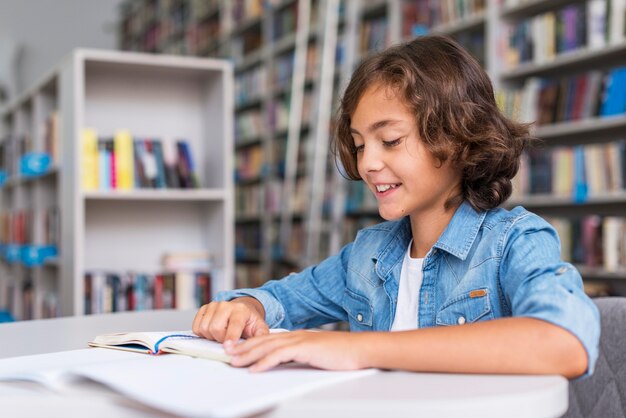 Kleiner Junge macht seine Hausaufgaben in der Bibliothek