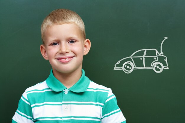 Kleiner Junge mit einem Auto auf der Tafel