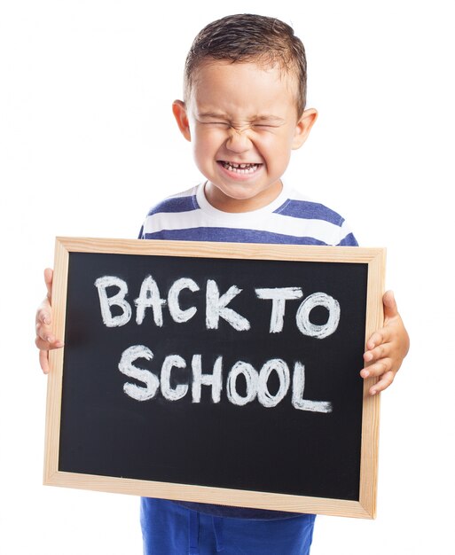 Kleiner Junge mit einer Tafel mit der Nachricht zu weinen &quot;back to school&quot;