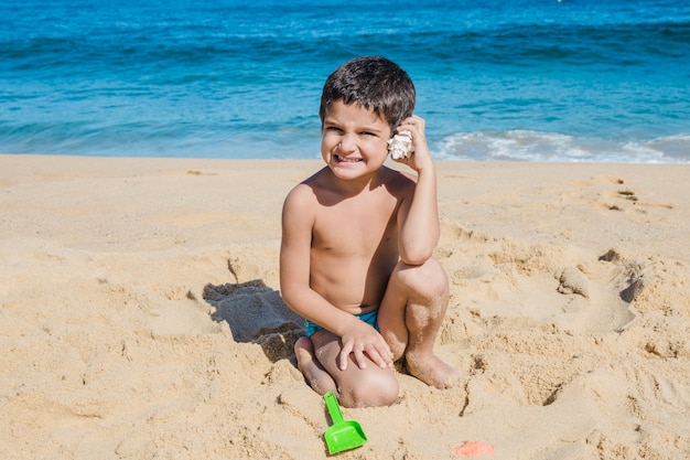 Kostenloses Foto kleiner junge mit schale auf dem ebeach