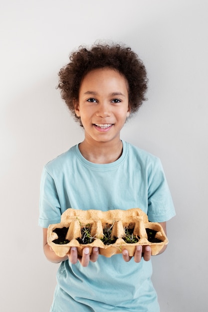 Kleiner Junge mit viel Grün in Upcycling-Topf gepflanzt