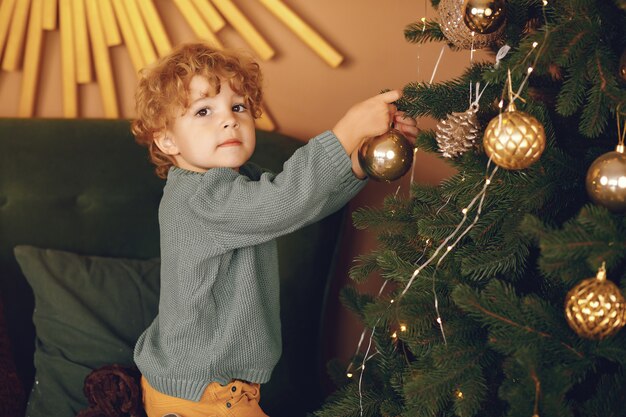 Kleiner Junge nahe Weihnachtsbaum in einer grauen Strickjacke