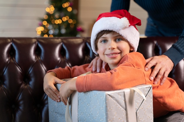 Kleiner Junge posiert neben einem Weihnachtsgeschenk