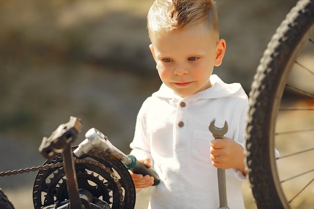 Kleiner Junge repariert sein Fahrrad in einem Park
