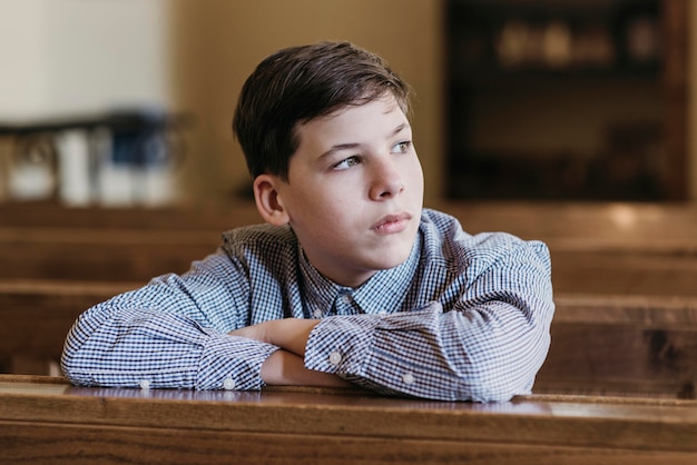 Kostenloses Foto kleiner junge schaut weg in der kirche