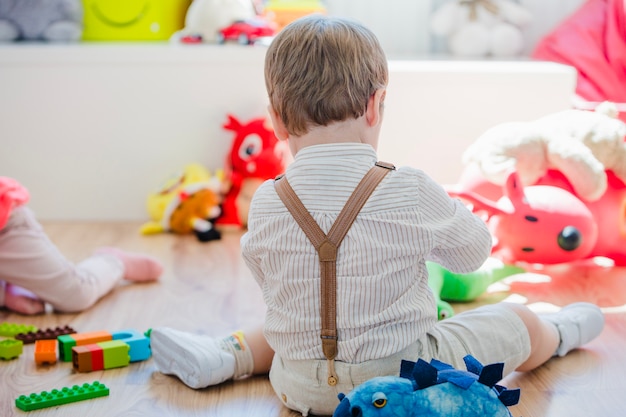 Kleiner Junge sitzt auf dem Boden spielen