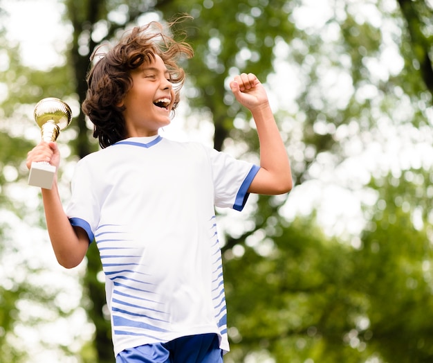 Kleiner Junge springt, nachdem er ein Fußballspiel gewonnen hat