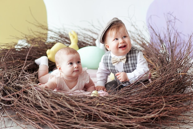 Kleiner Junge und Mädchen, die im natürlichen Nest mit bunten Ostereiern sitzt.