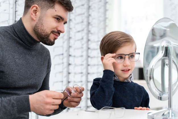 Kleiner Junge und Vater im Laden, die Brille anprobieren