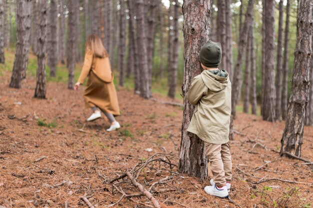 Kleiner Junge versteckt sich vor seiner Mutter im Wald